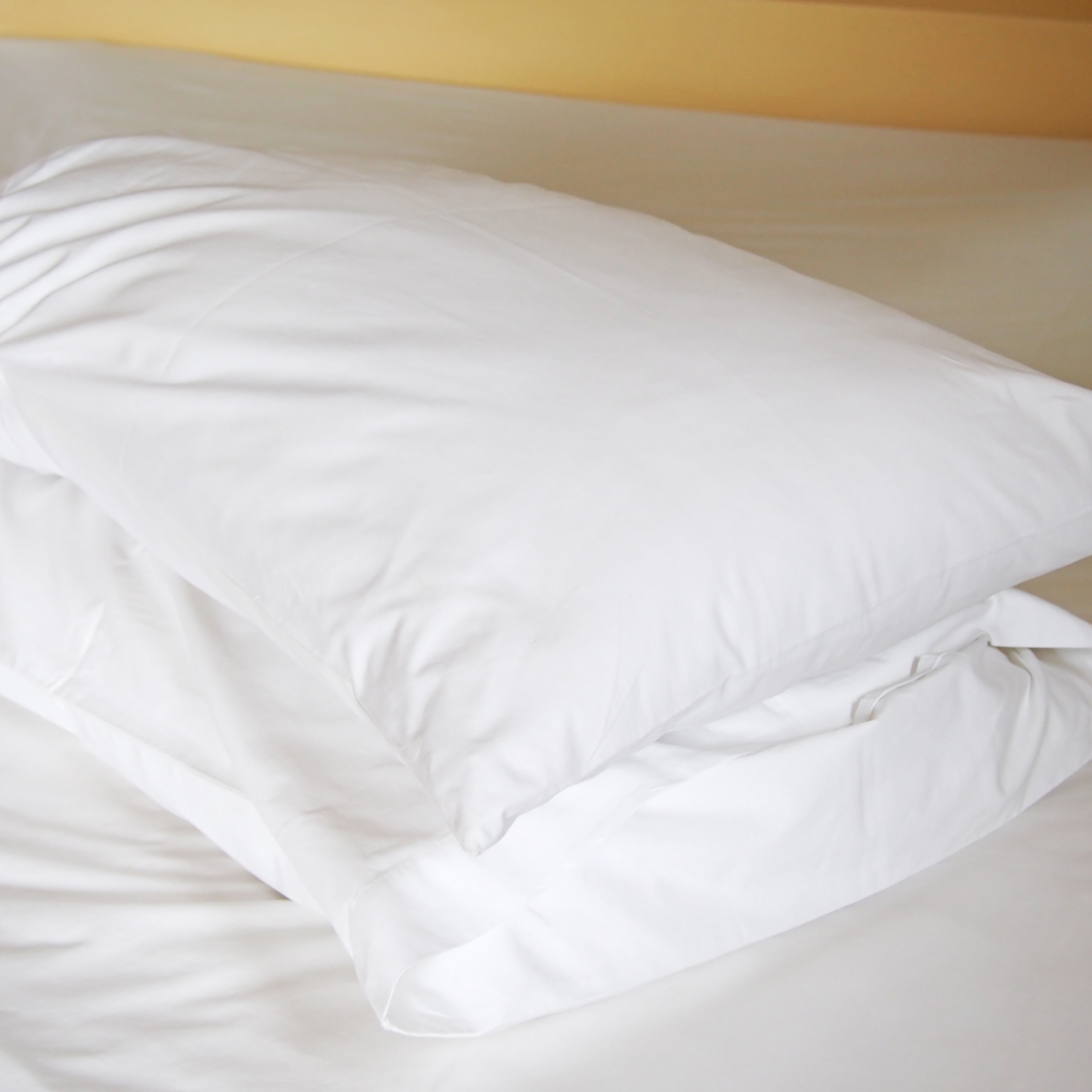 Crisp white bed sheets in a serene setting, showcasing their softness and skin-friendly material.