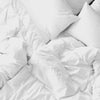 Close-up of luxurious white cotton bed sheets, highlighting their smooth texture and gentle touch on the skin.