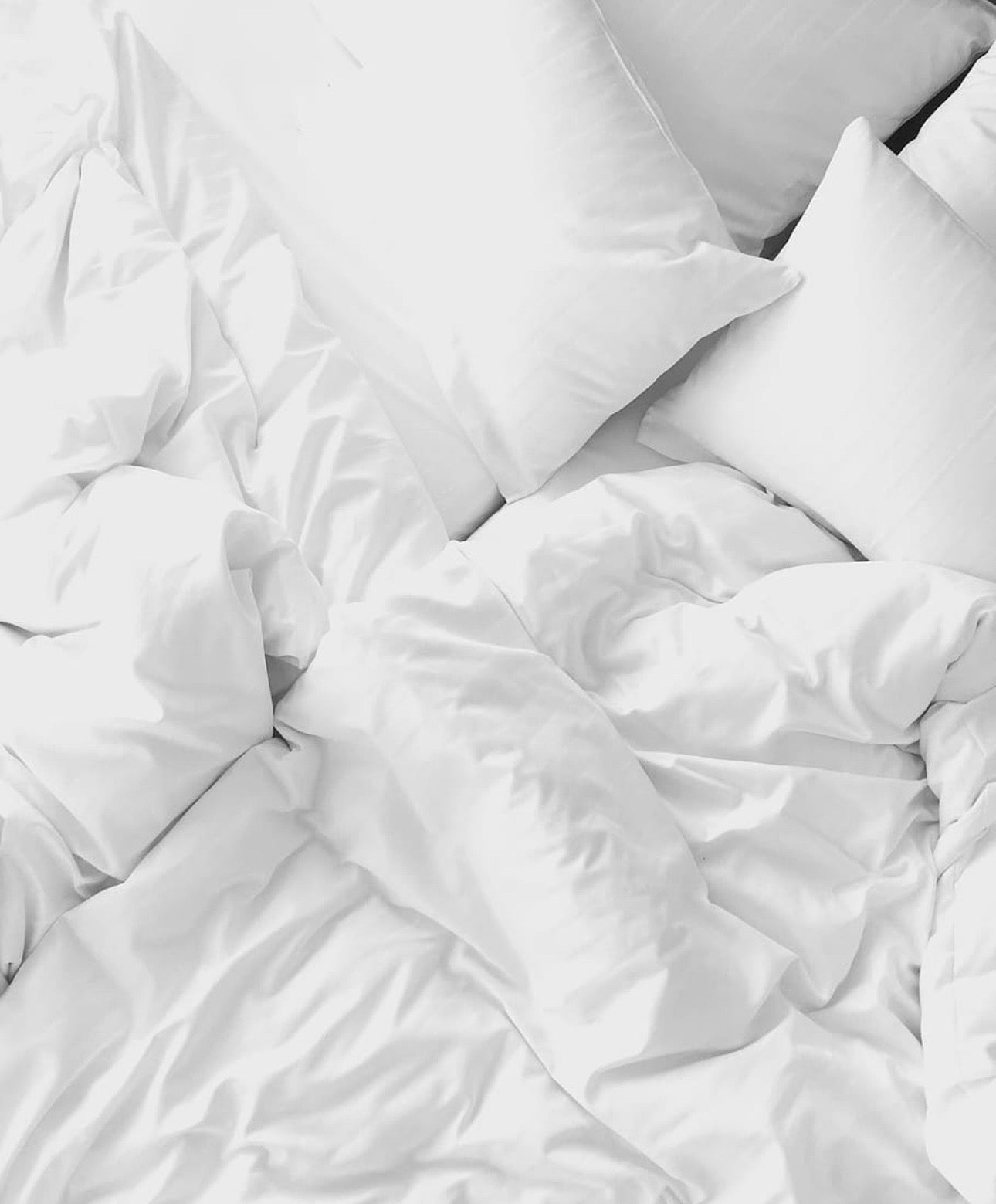 Close-up of luxurious white cotton bed sheets, highlighting their smooth texture and gentle touch on the skin.
